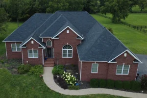 Aerial view of a brick home in Danville with a newly installed dark gray asphalt shingle roof and manicured landscaping.