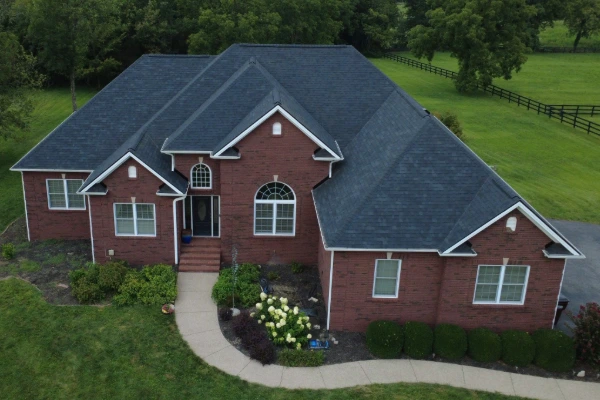 Aerial view of a brick home in Danville with a newly installed dark gray asphalt shingle roof and manicured landscaping.