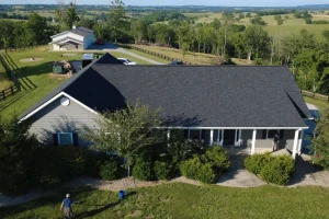 Roofing crew finishing a charcoal asphalt shingle roof replacement on a rural Kentucky ranch-style home.